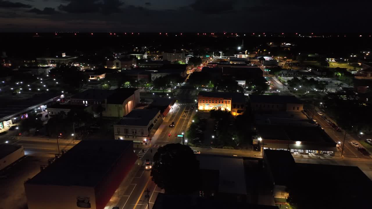 Traffic scene on junction in american town at night. Lighting cityscape after sunset in Florida. Aerial panning wide shot. Houses, homes and suburb neighborhood of Plant City, USA.