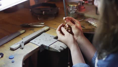 close up of hands of caucasian female jeweller making ring in workshop