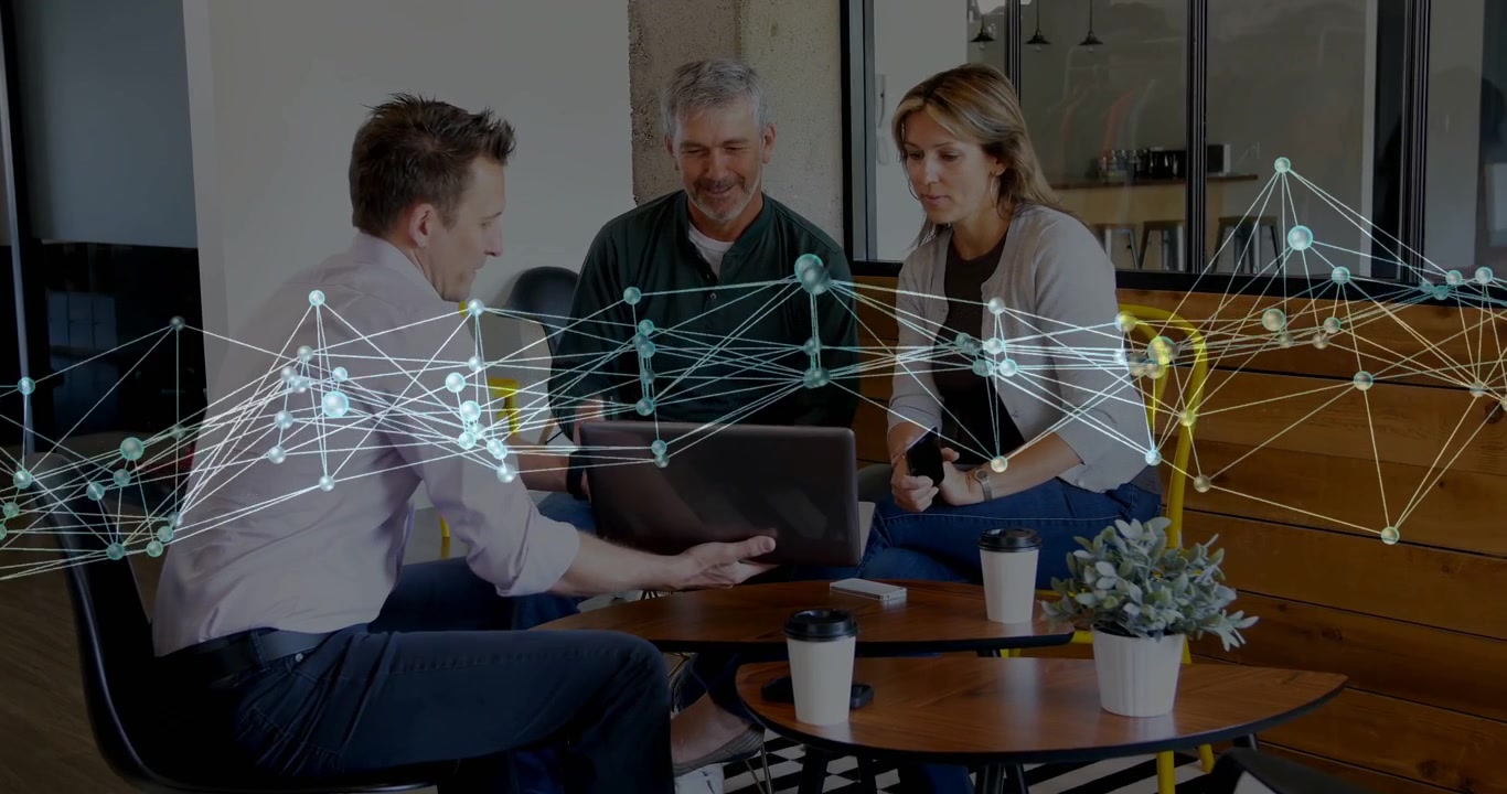 Team læner sig ind, manden til venstre viser bærbar computer, gennemgår forretningsdata med bevægeligt netværks-overlay.