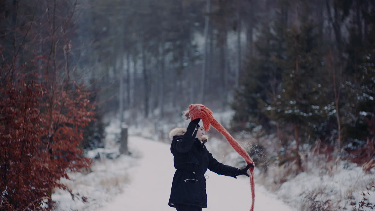 позитивная женщина прыгает на снегу и играет с шарфом зимой 1