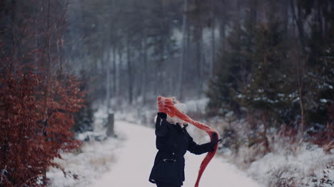 Positive-Frau,-Die-Im-Winter-Auf-Schnee-Springt-Und-Mit-Schal-Spielt-1