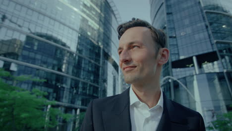 portrait of handsome caucasian man in suit standing outdoors smiling and looking aside, close up
