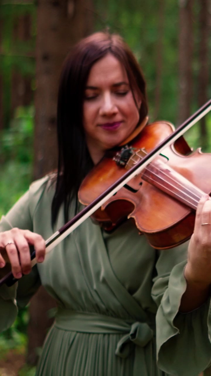 Donna che suona il violino in un ambiente boschivo