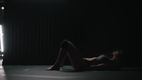a sexy athletic woman in lingerie dances wet in oil in the gym near the gym near the gym benches and barbells.