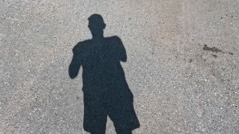 a person's shadow dancing on a textured ground.