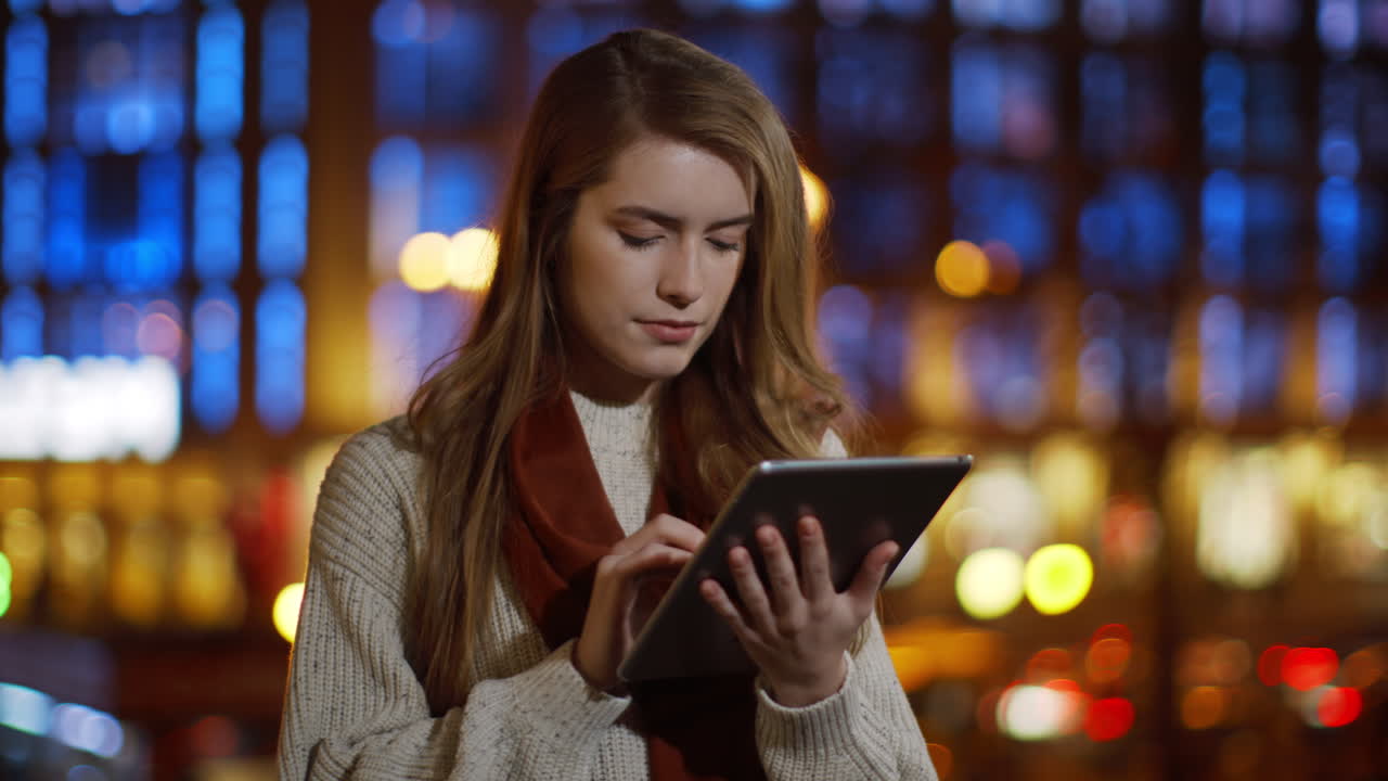 Serious girl surfing internet on tablet outside. Woman looking tablet screen