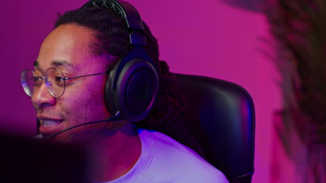 a young black man wearing headphones and glasses is playing a video game.