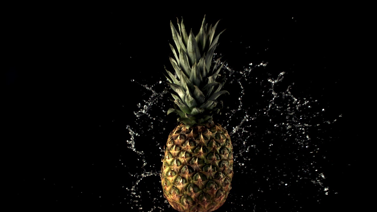 Water Splashing on a Fresh Pineapple Against a Black Background