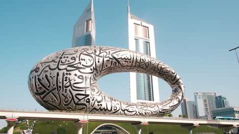 metro train passing in front of dubai, museum of the future and emirates towers