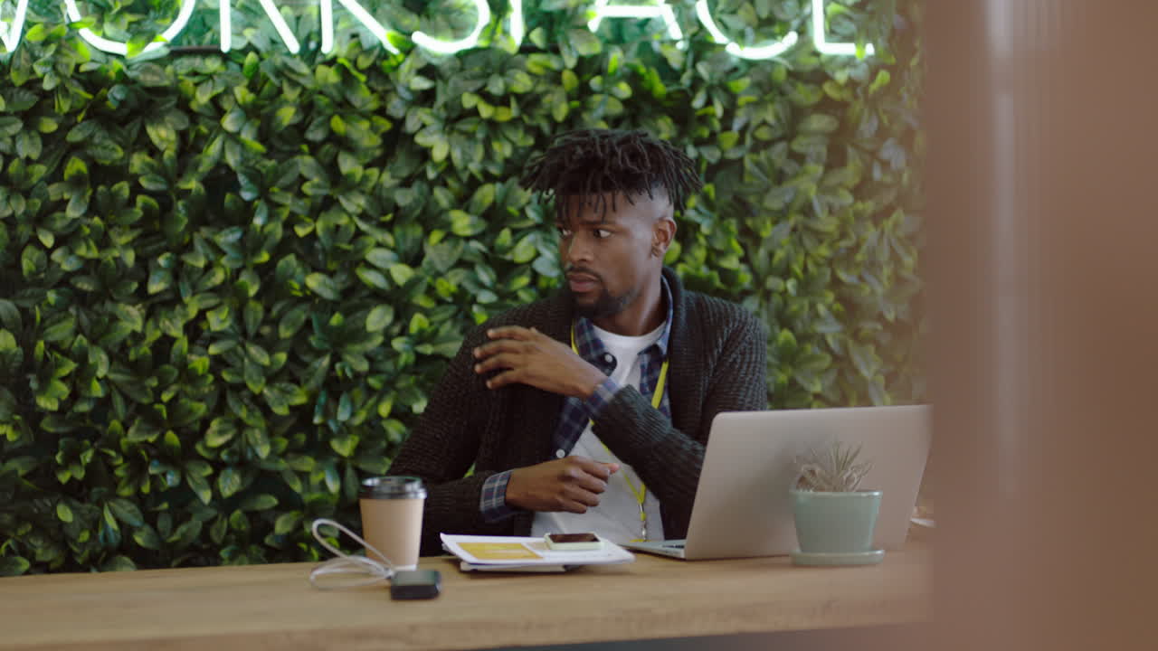bored businessman at work young african american man looking unmotivated expressing boredom lazy employee tired stretching arms in workplace