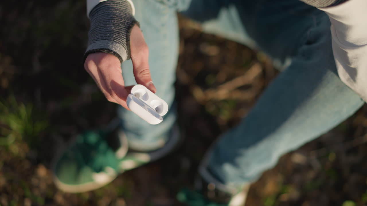 Una persona inspecciona minuciosamente la funda de los auriculares, una mujer revisa diligentemente su caja de auriculares y accesorios, una persona examina metódicamente la funda que contiene sus auriculares con atención y cuidado.