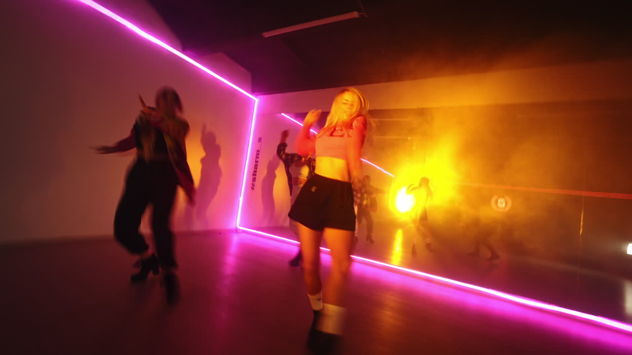 Stylish girls performing contemporary dance in the studio club. Girls trio dancing hip hop in the room with pink light.