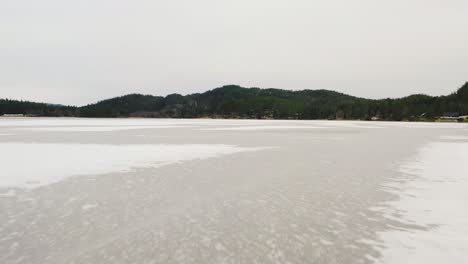 low flight over the surface of the water of an icy natural lake up north in norway