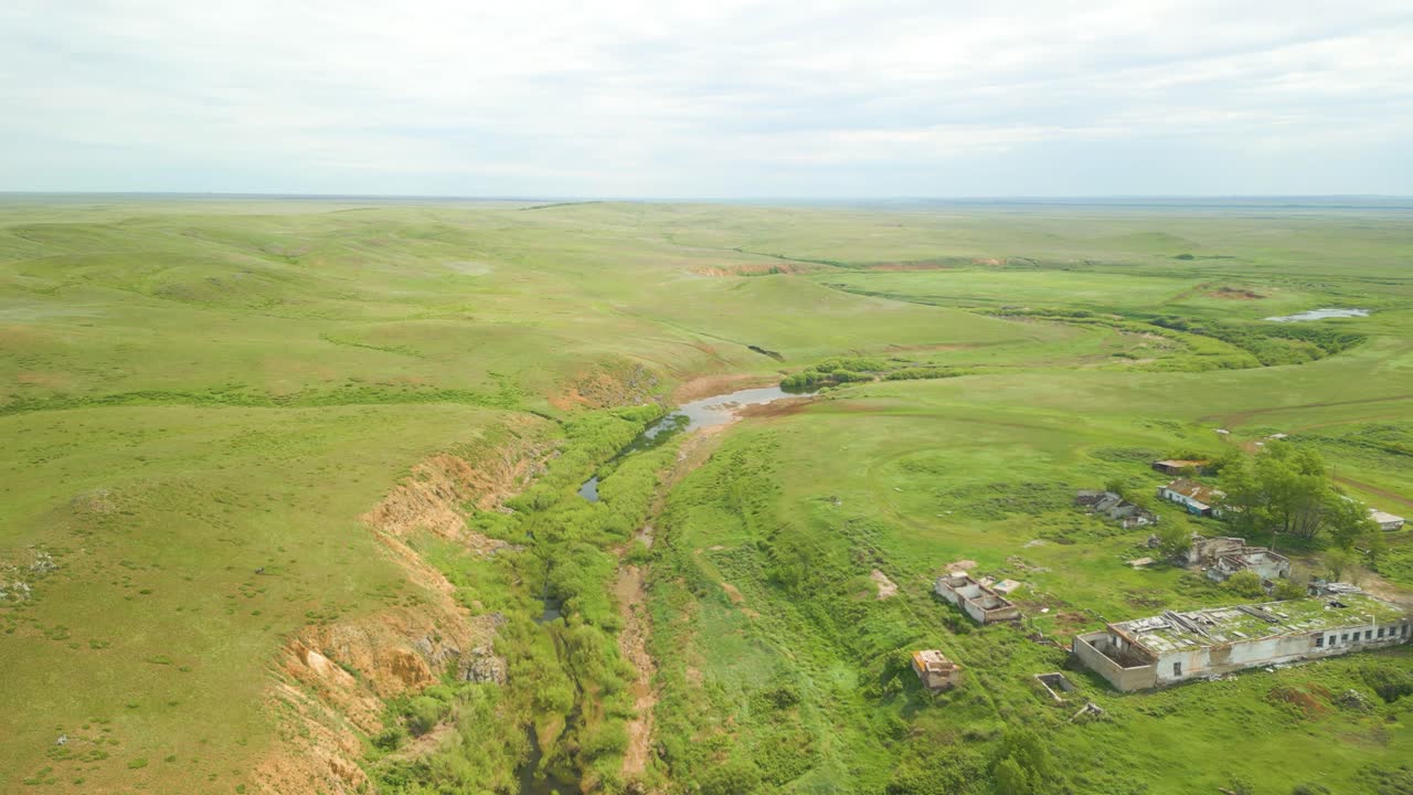 Aerial View of Abandoned Buildings and River in a Grassland