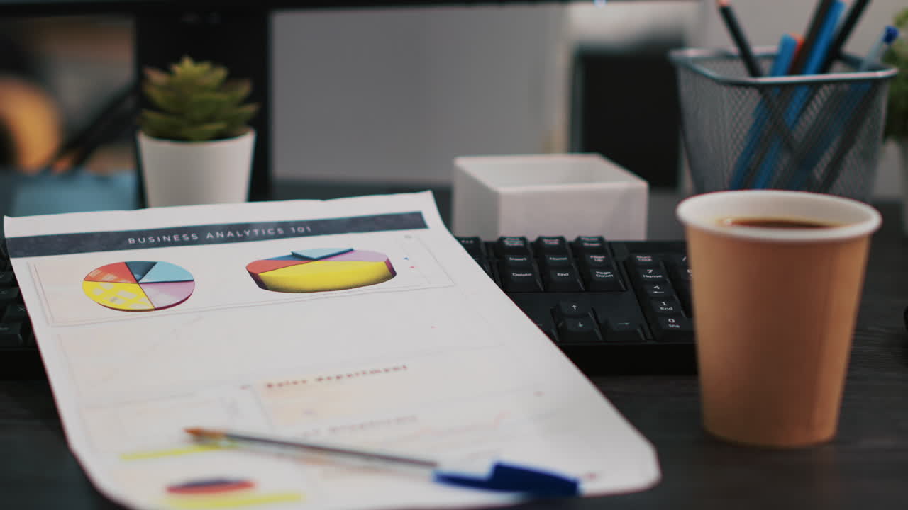 Documenti aziendali con grafici e tabelle economiche vicino a una tazza di caffè, primo piano
