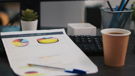 company files containing economic graphs and charts near coffee cup, close up