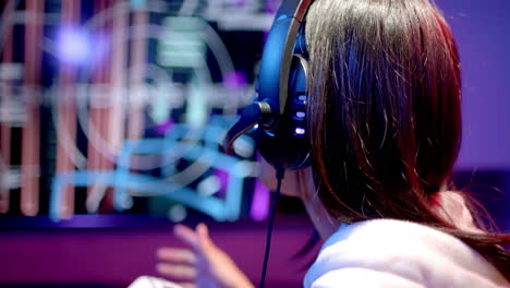 wearing headset and playing video game, teenage girl focusing on screen