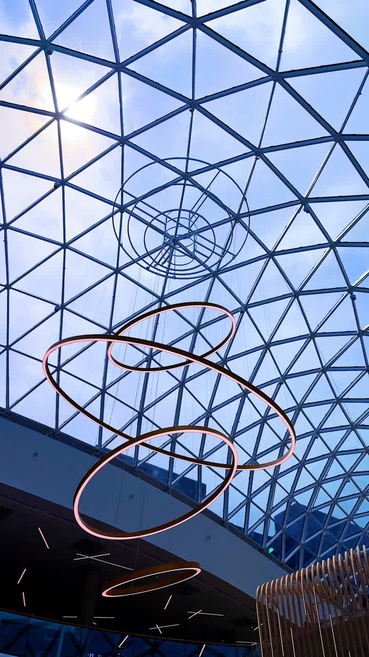 Geometric modern architecture. A striking glass ceiling features intricate geometric patterns and hanging sculptures, showcasing modern architecture