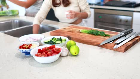 two people organize fresh vegetables on a kitchen counter under bright lighting, creating a vibrant and dynamic culinary scene