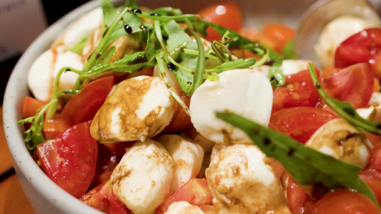 Primo piano di una fresca insalata Caprese servita con glassa balsamica e basilico a un buffet