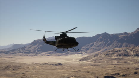 military helicopter flying over desert mountains