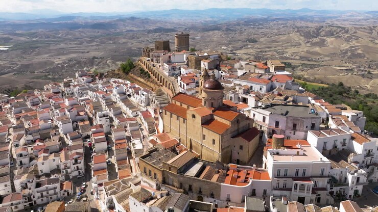 Città collinare densamente popolata con la Chiesa Madre di Pisticci in Provincia di Matera, Basilicata, Italia. Scatto aereo con drone.