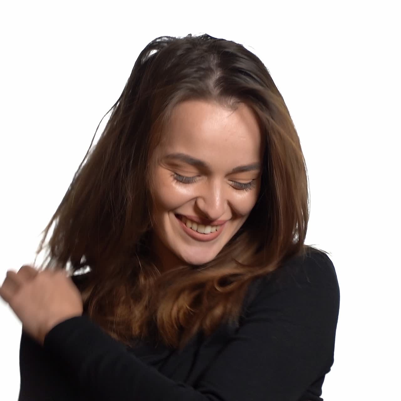 beautiful woman with long hair and in black sweater is sending an air kiss on a white background in the studio. Close-up