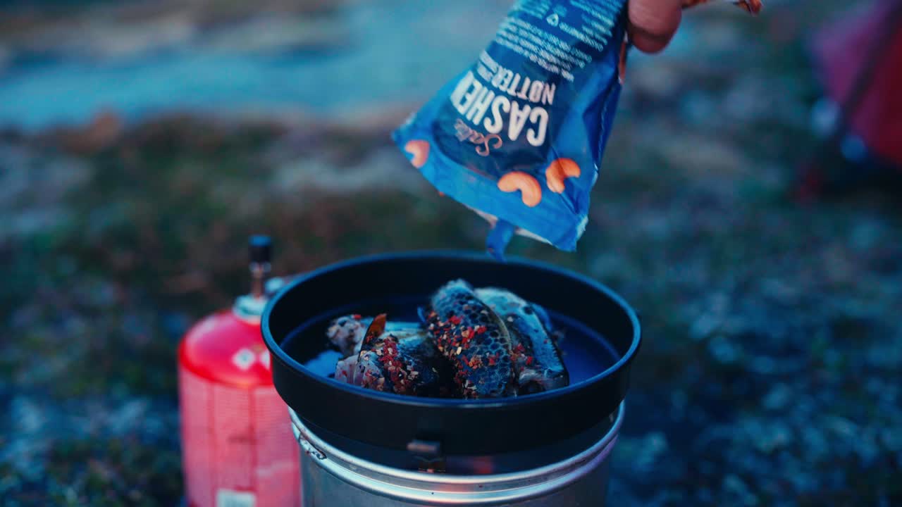 cocinar pescado fresco y sazonado con una estufa de gas portátil en el campamento