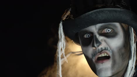 crazy man with horrible halloween skeleton makeup making faces, showing tongue, trying to scare