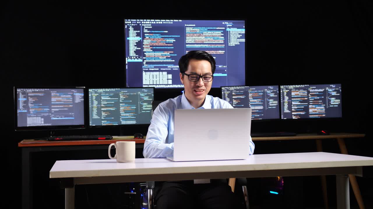 programador trabajando en una computadora portátil con múltiples monitores