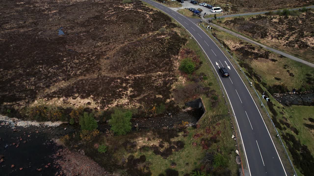 Cinematic Aerial shot of a black car driving through Scottish highlands on Isle of Skye