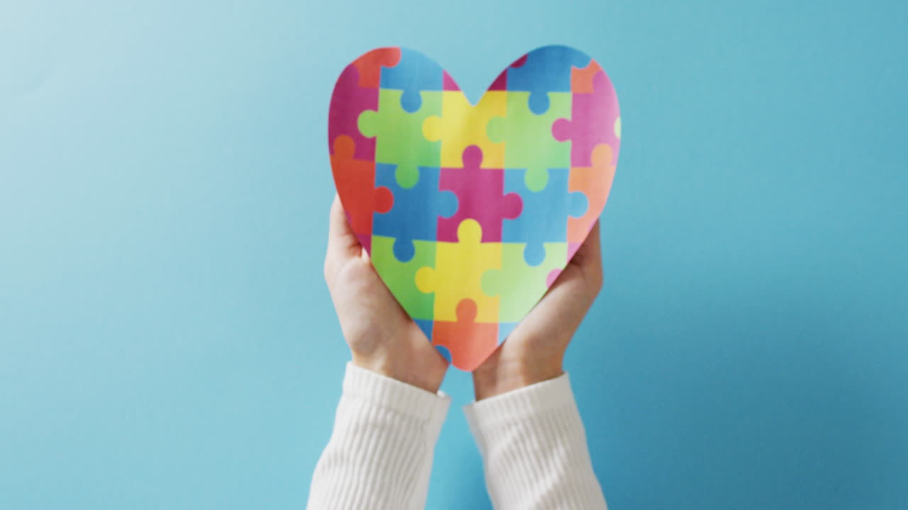 Video di mani che tengono un cuore a puzzle su sfondo blu con spazio per il testo