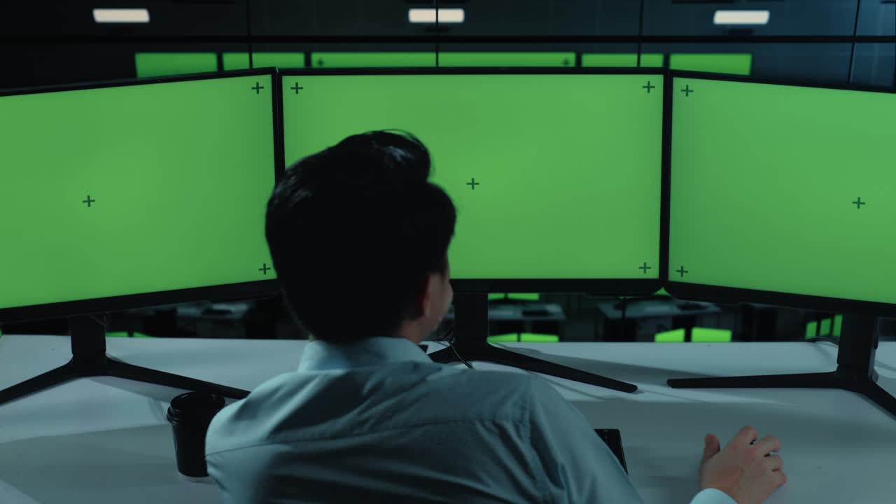 지친 아시아인 남자가 사무실에서 모의 여러 컴퓨터 모니터와 함께 작업하는 동안 는 뒤의 모습