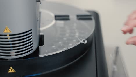 mano caucásica de un científico poniendo una sonda en una máquina para pruebas - de cerca