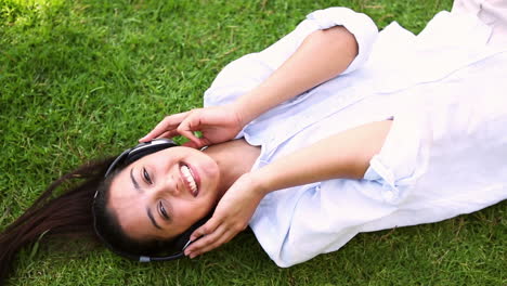 pretty girl lying on the grass listening to music