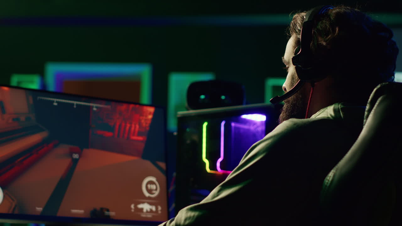 Muž online komunikuje se spoluhráči při hraní videoher na herním PC a vytváří vítěznou strategii.