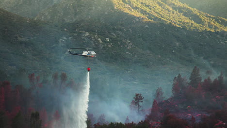 firefighting helicopter bucket dropping fire retardant over bush fire