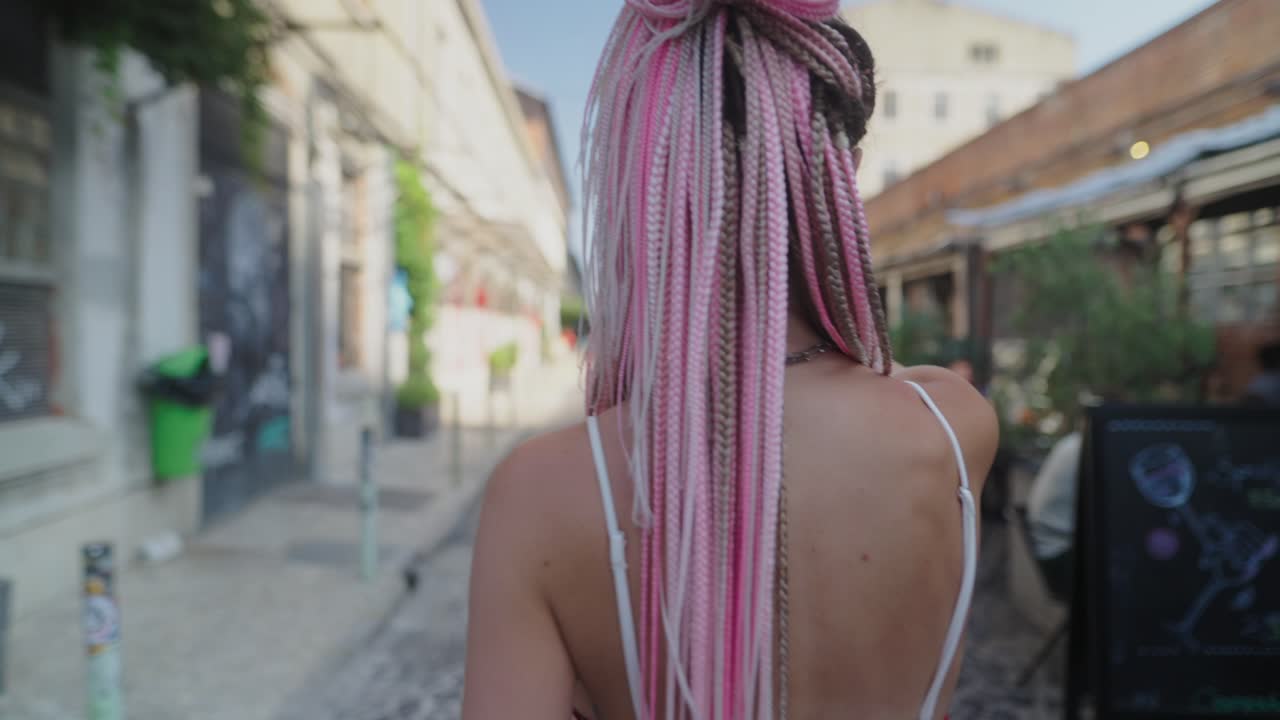 Woman with Pink Braids Walking on City Street