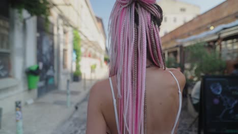 woman with pink braids walking on city street