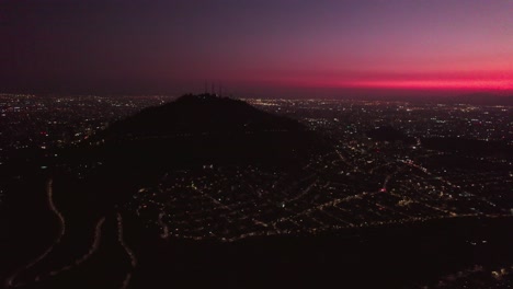 Toma-Aérea-Sobre-El-Cerro-San-Cristobal-Con-Una-Vibrante-Puesta-De-Sol-Sobre-Santiago