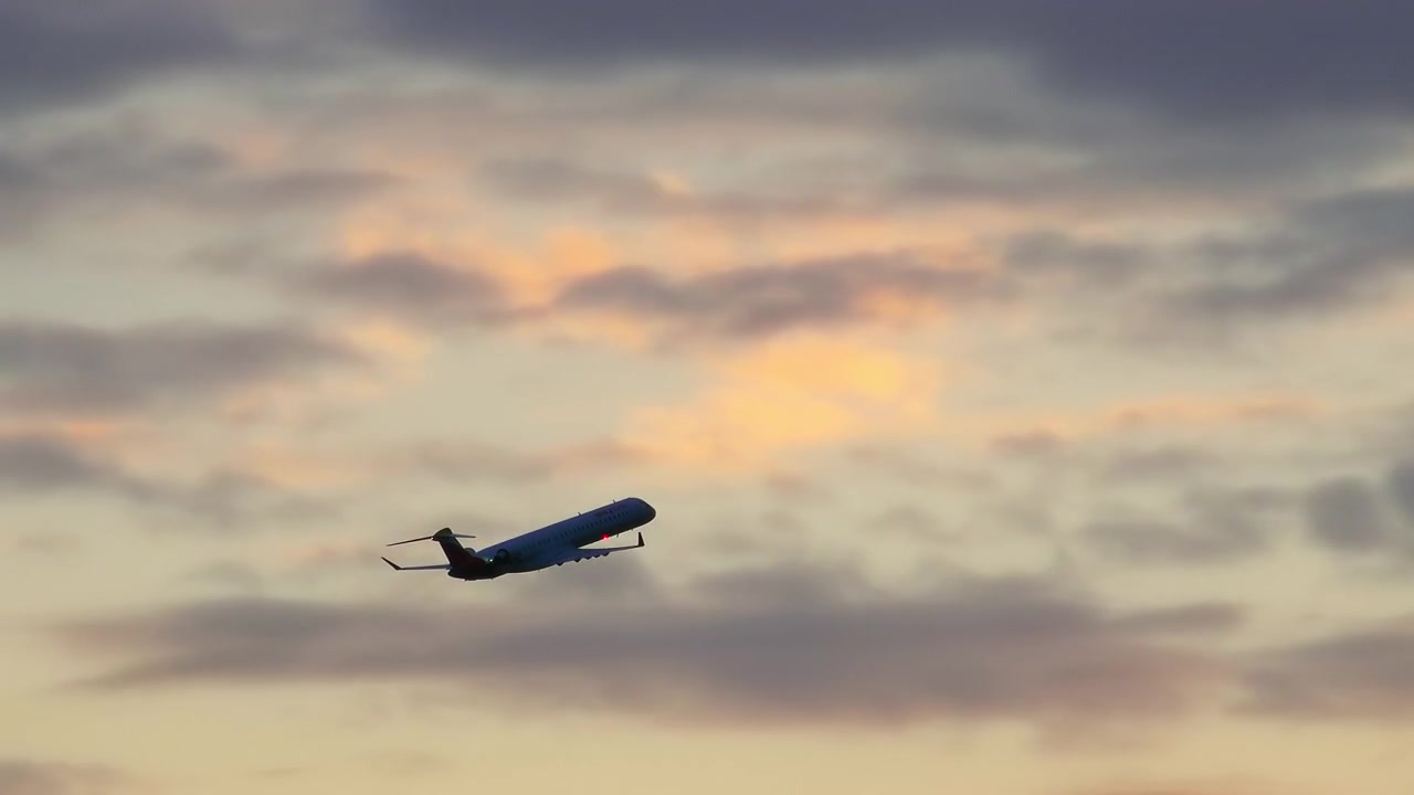 Aereo di linea commerciale in ascesa in un cielo nuvoloso al tramonto