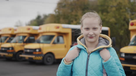 Portrait-of-a-female-pupil-against-the-background-of-a-typical-yellow-school-bus