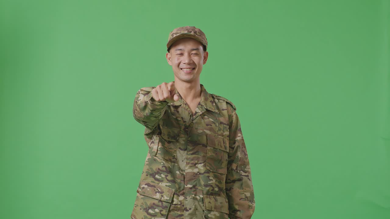 Asian Man Soldier Smiling And Touching His Chest Then Pointing At You While Standing In The Green Screen Background Studio