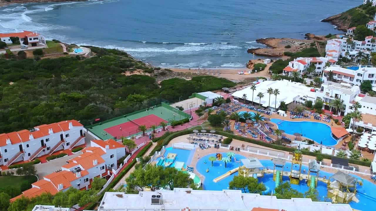 vistas aéreas de personas de vacaciones, jugando al tenis, en la piscina y relajándose en la playa en menorca, españa