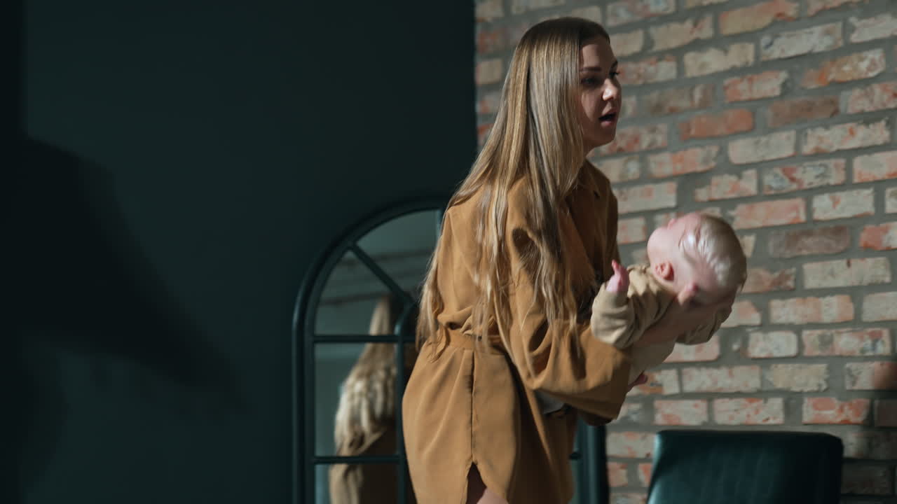 Long-haired young woman swaying her infant child. Mother waving her son to make him sleep.