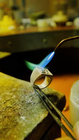blue torch flame heats engraved et signet ring in intense close up crafting shot