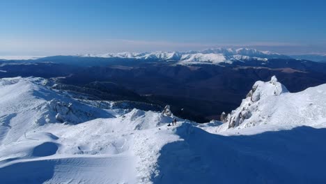 Vista-De-Drones-Sobre-El-Pico-De-La-Montaña-Ciucas-Y-La-Montaña-Bucegi-En-El-Fondo-En-Rumania-Durante-El-Invierno