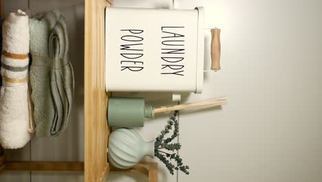 organized laundry room shelf with towels and laundry powder container