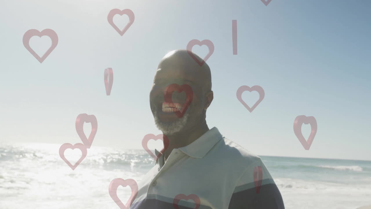 Animation of heart shapes floating around man smiling at beach