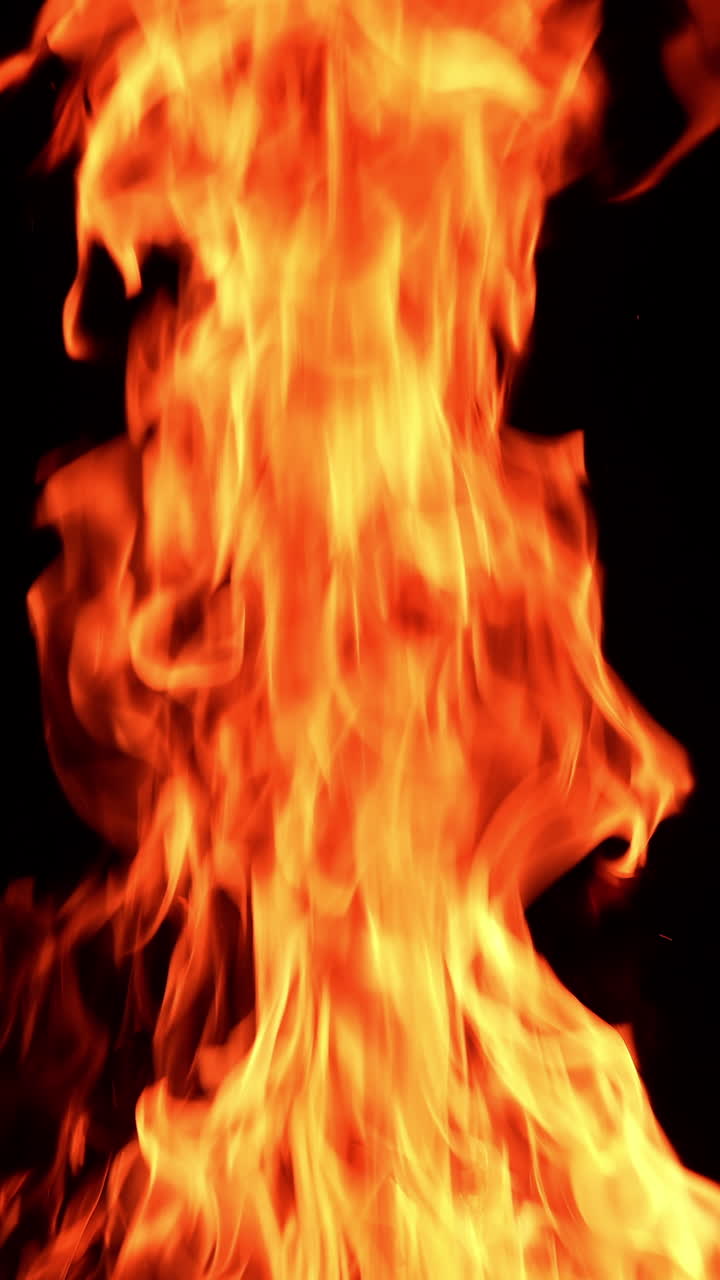 Huge bonfire rising up in the darkness. Dangerous red flame going up at night. Vertical video